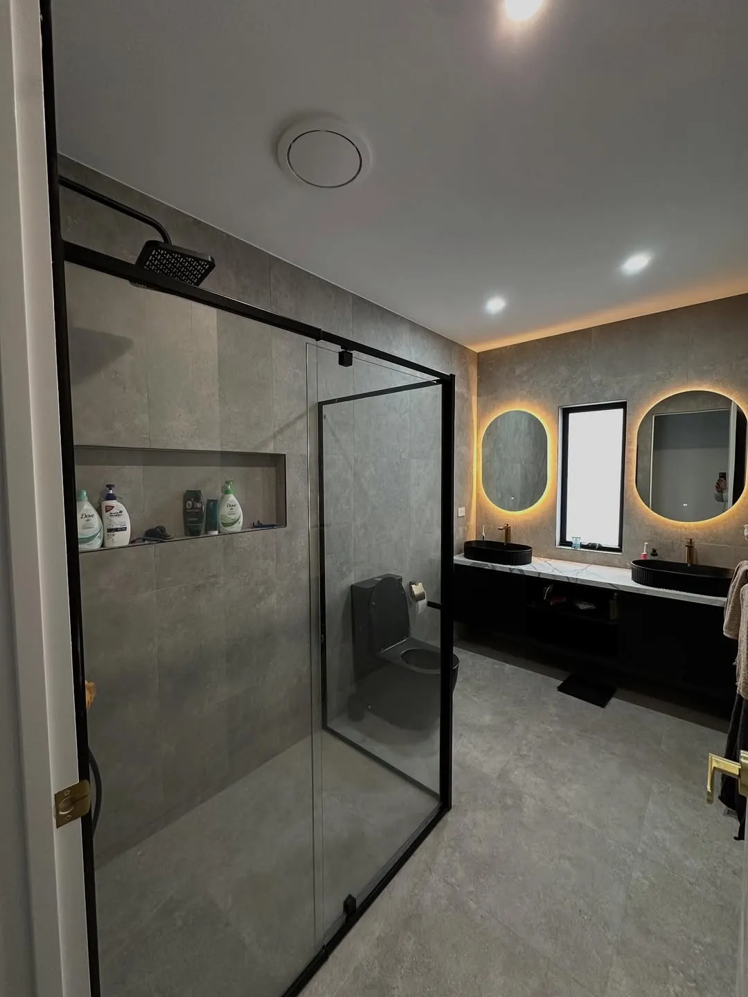 Dark concrete-look bathroom with LED mirrors