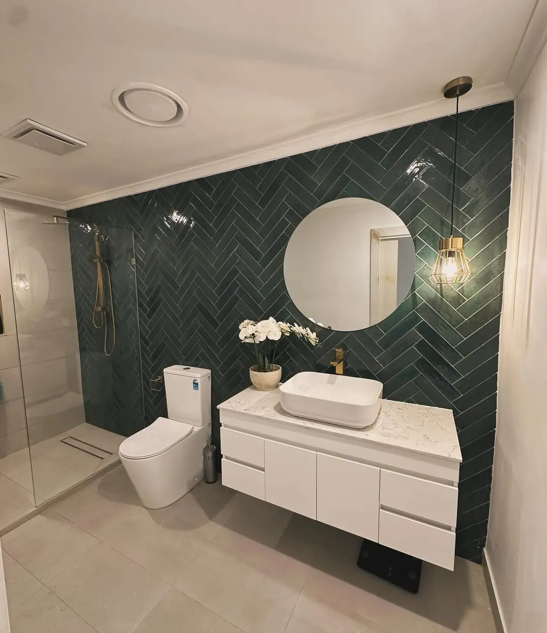 Bathroom with emerald green herringbone feature wall and brass tapware